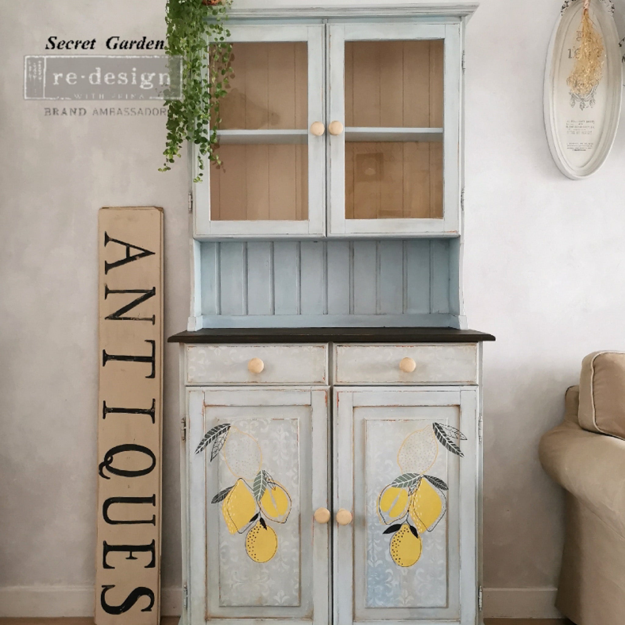A country style small hutch top cabinet refurbished by Secret Garden is painted a pale blue and features ReDesign with Prima's Lemon small transfer on its bottom doors.