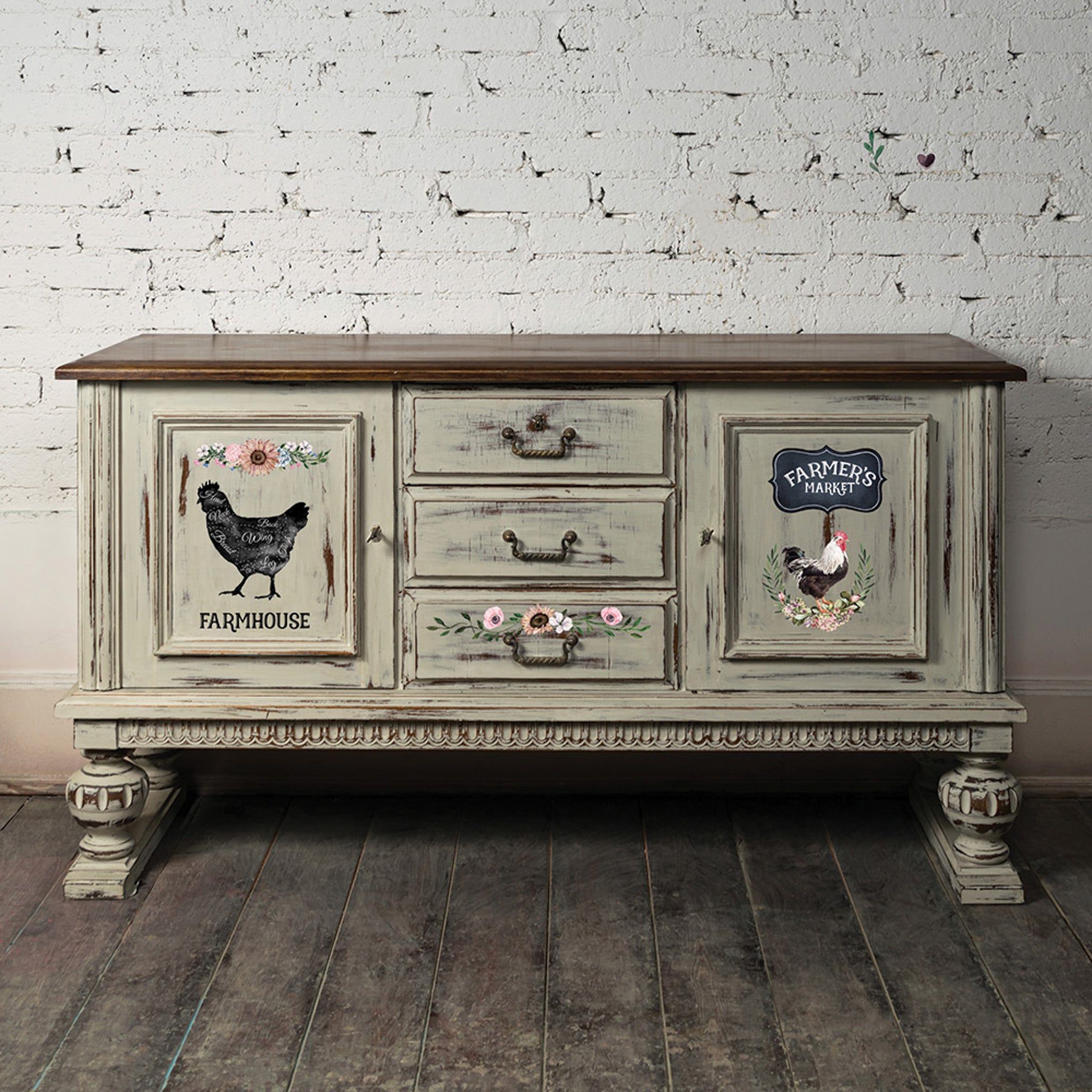 A vintage buffet table is painted a distressed beige with a natural wood top and features ReDesign with Prima's Morning Farmhouse small transfer on its doors and bottom drawer.