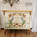A vintage 3-drawer dresser refurbished by Secret Garden is painted faux antique limewash with bronze accents and features ReDesign with Prima's Peacock Paradise small transfer on the drawers.