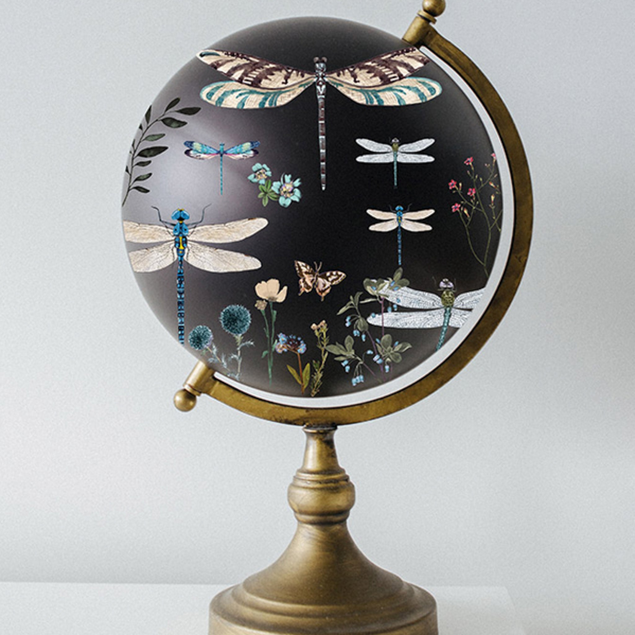 A world globe is painted black and features ReDesign with Prima's Spring Dragonfly small transfer on it.