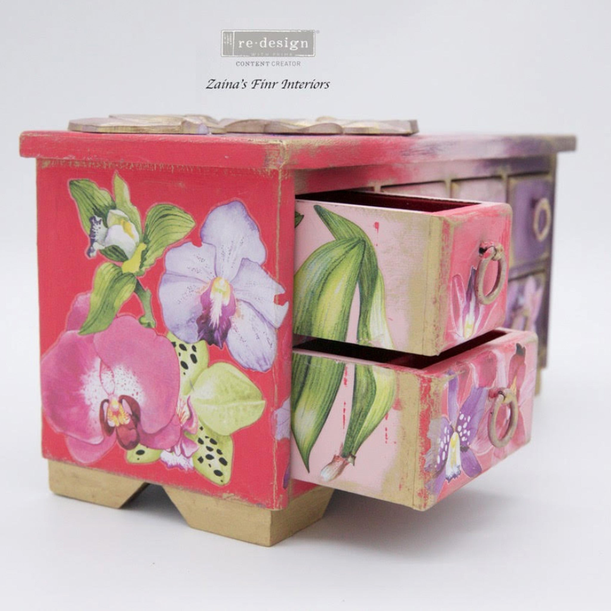 A small jewely box with drawers refurbished by Zaina's Fine Interiors is painted an ombre of coral prink to purple and features ReDesign with Prima's Sunset Tropics small transfer on it.