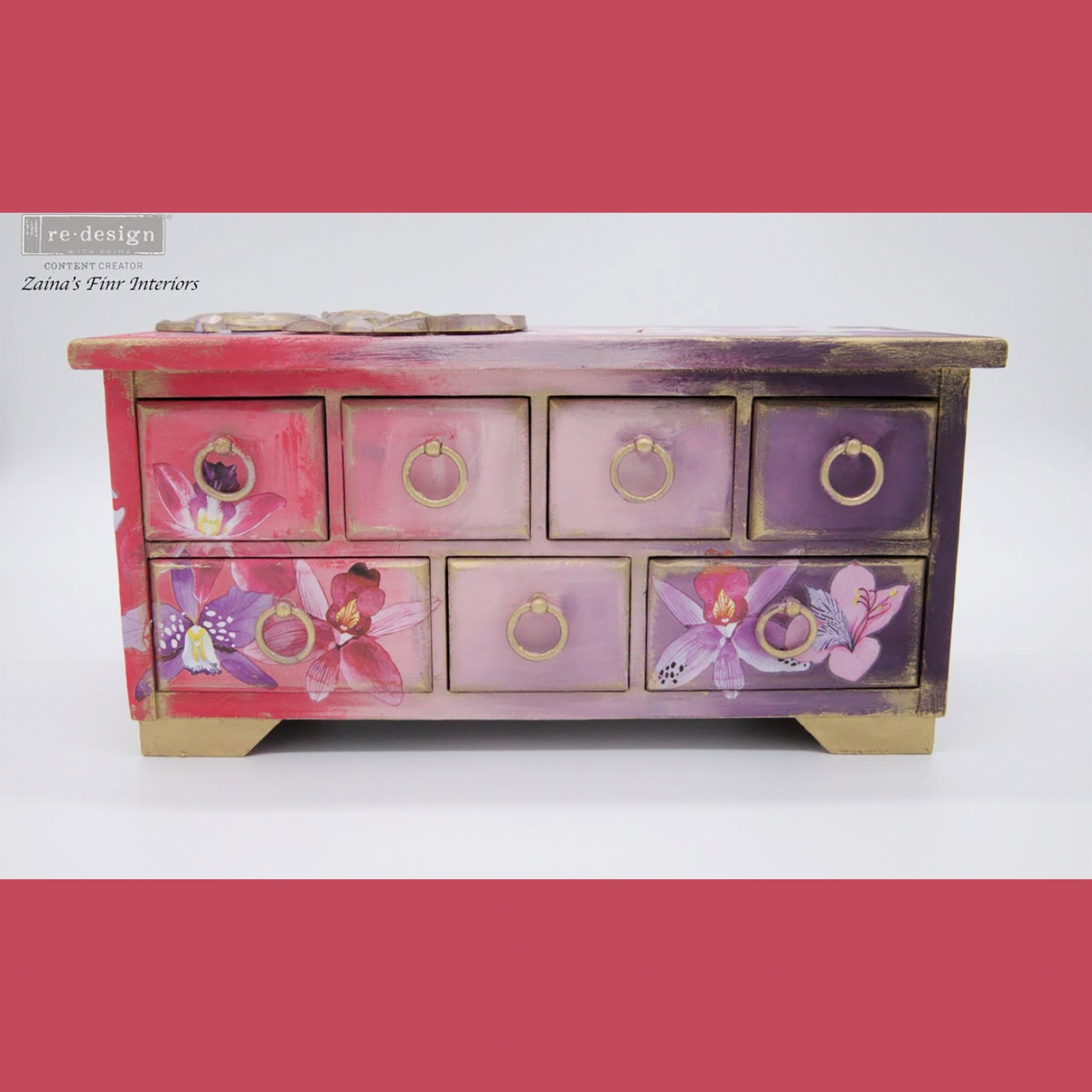 A small jewely box with drawers refurbished by Zaina's Fine Interiors is painted an ombre of coral prink to purple and features ReDesign with Prima's Sunset Tropics small transfer on it. Coral pink borders are on the top and bottom.