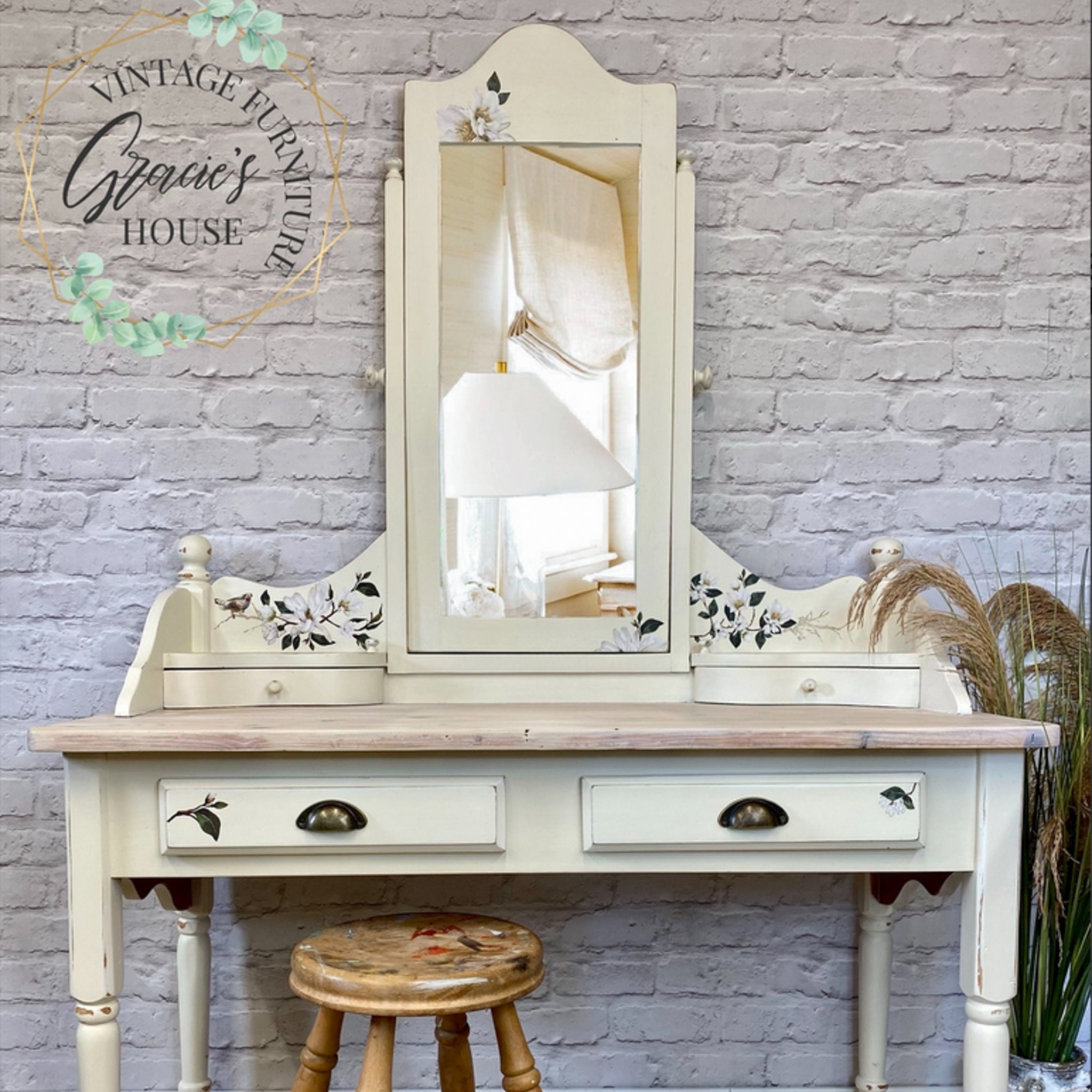 A vintage vanity refurbished by Gracie's House Vintage Furniture is painted a light cream and features ReDesign with Prima's White Magnolia small transfer on it.