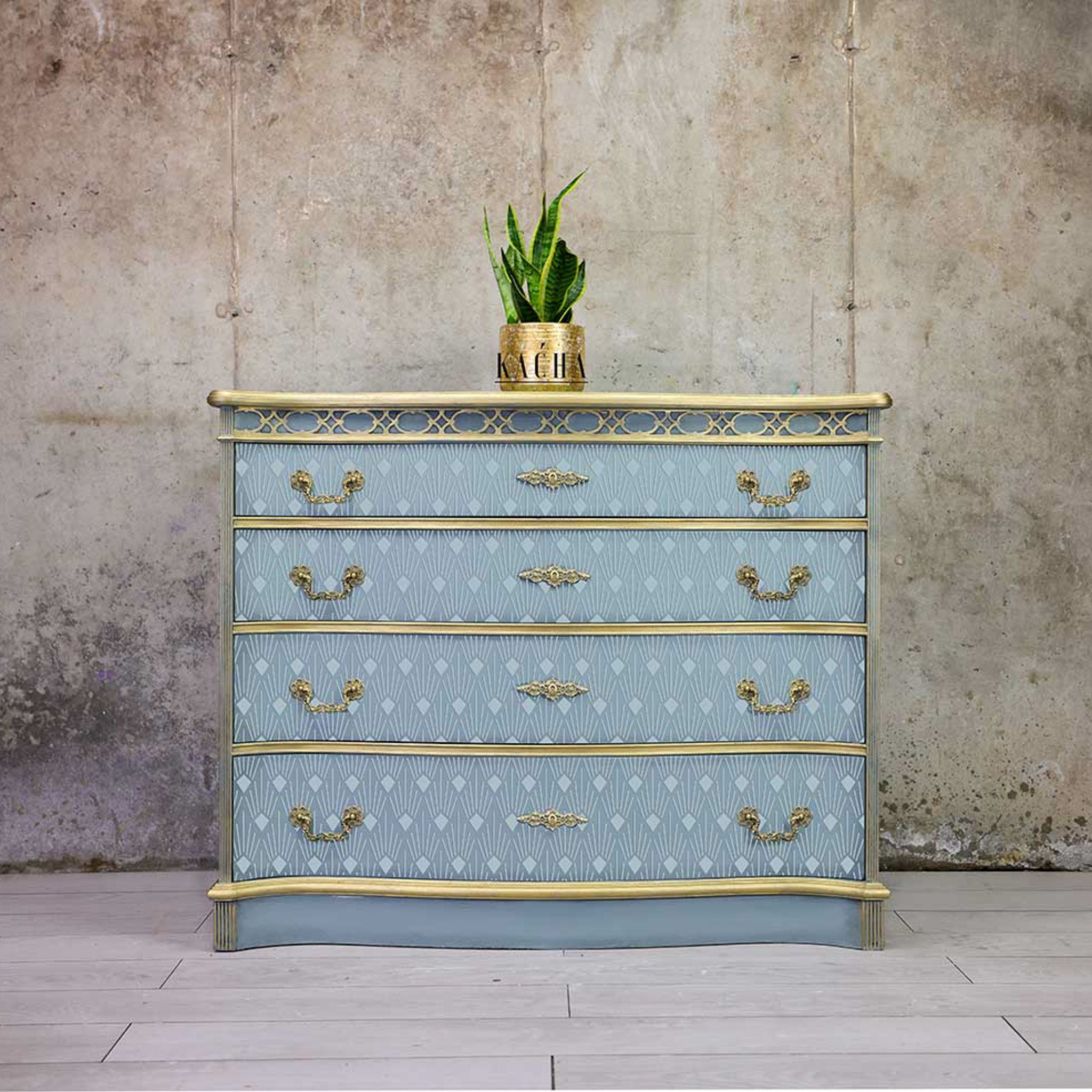A 4-drawer dresser painted light blue with gold accents features ReDesign with Prima's Sunlit Diamonds stencil in an even lighter blue on its drwers.
