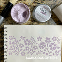 White stock paper with flowers in the color Roycroft Rose. Displayed is Roycroft Rose chalk paste with the lid off. To the right is a lid of the chalk paste Roycroft Rose. A white Maika Daughters logo is on the bottom right.