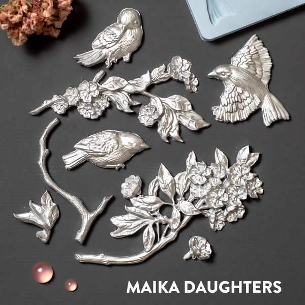 Silver silicone castings of small sparrow birds and branches with flower blooms.