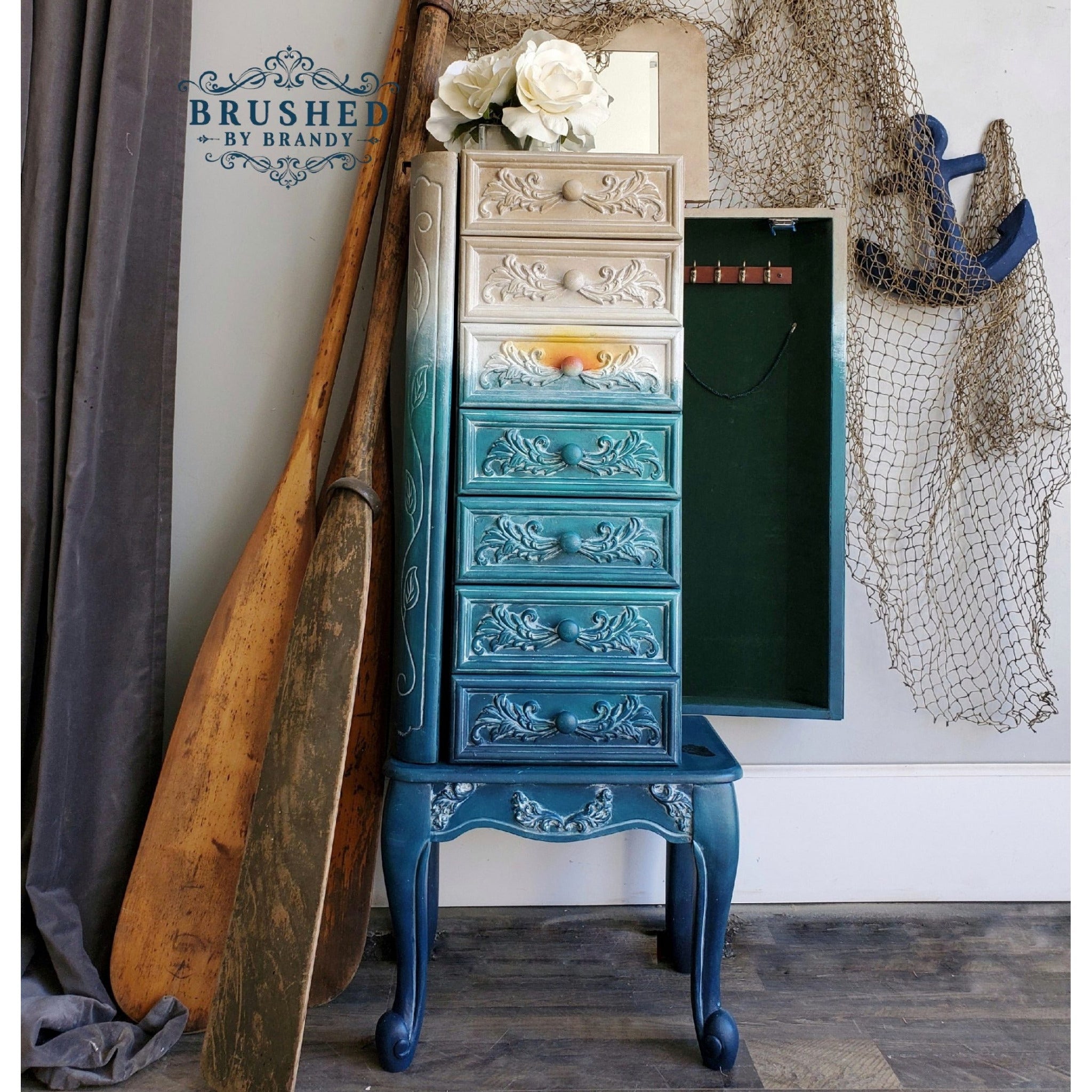 A vintage standing jewelry armoire refurbished by Brushed by Brandy is painted an ombre of tan down to blue and features ReDesign with Prima's Baroque Swirls silicone mold castings on it.