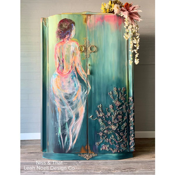 A vintage storage cabinet refurbished by Niss & That Leah Noell Design Co. is painted a blend of greens and features the Cherry Blossoms mould towards the bottom right.
