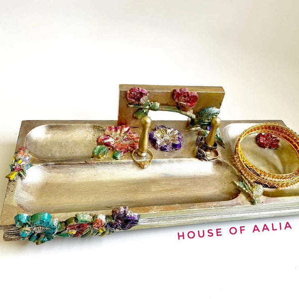 A gold jewelry tray decorated with the cherry blossoms mold. On the bottom right corner is magenta text reading; House of Aalia.