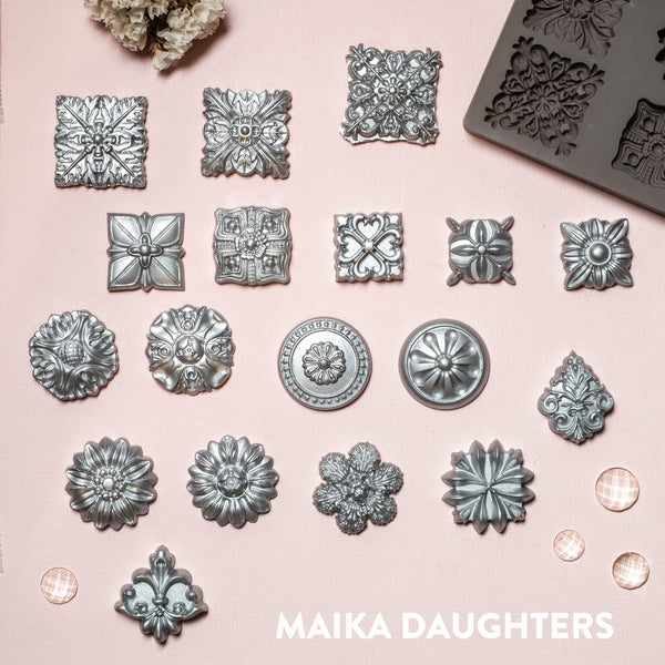 18 Curio Trinkets silver mold castings on a pink background. A white Maika Daughters logo on the bottom right.