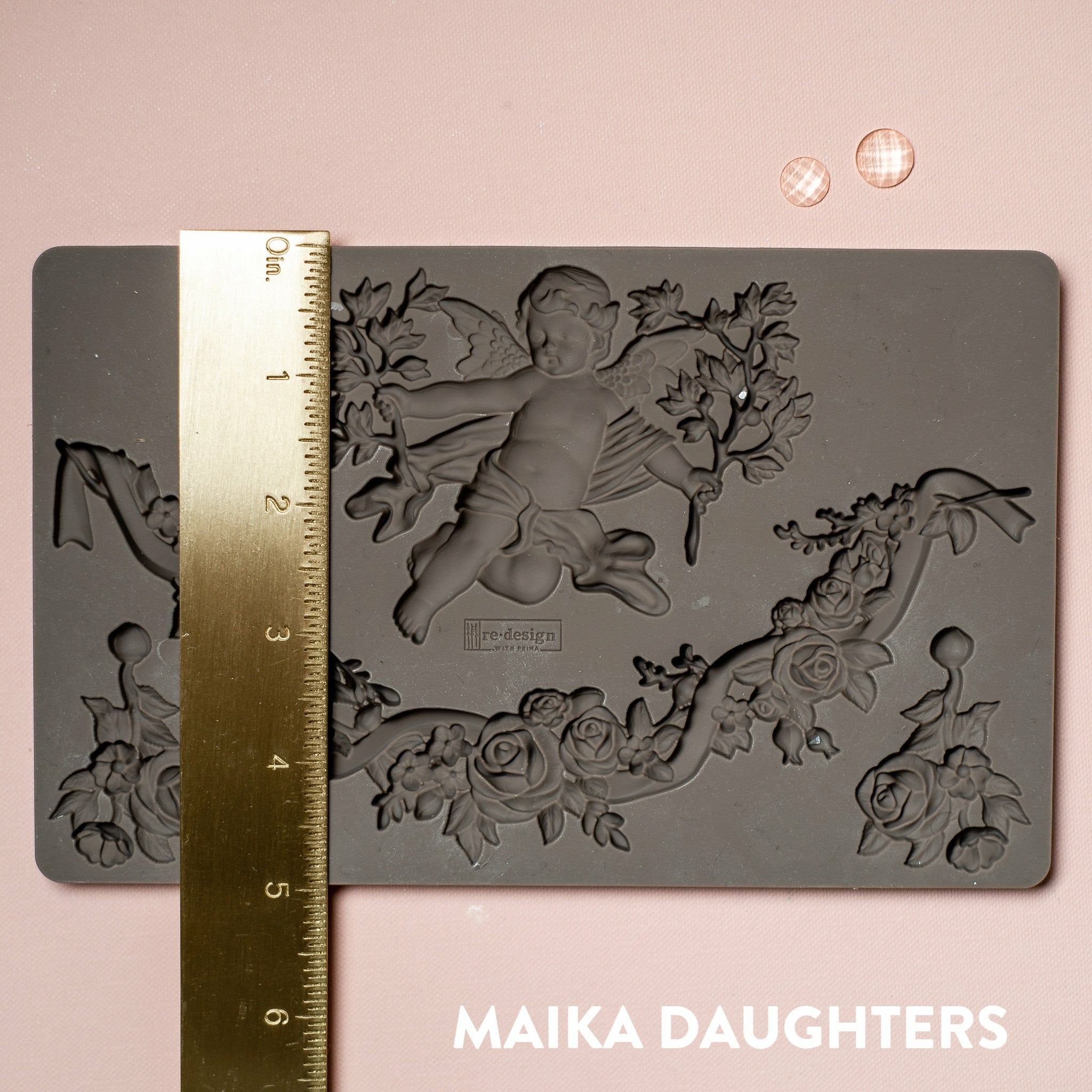 A brown silicone mould of ReDesign with Prima's Divine Floral silicone mould is on a light pink background. A gold ruler reading 5 inches sits on the mould.