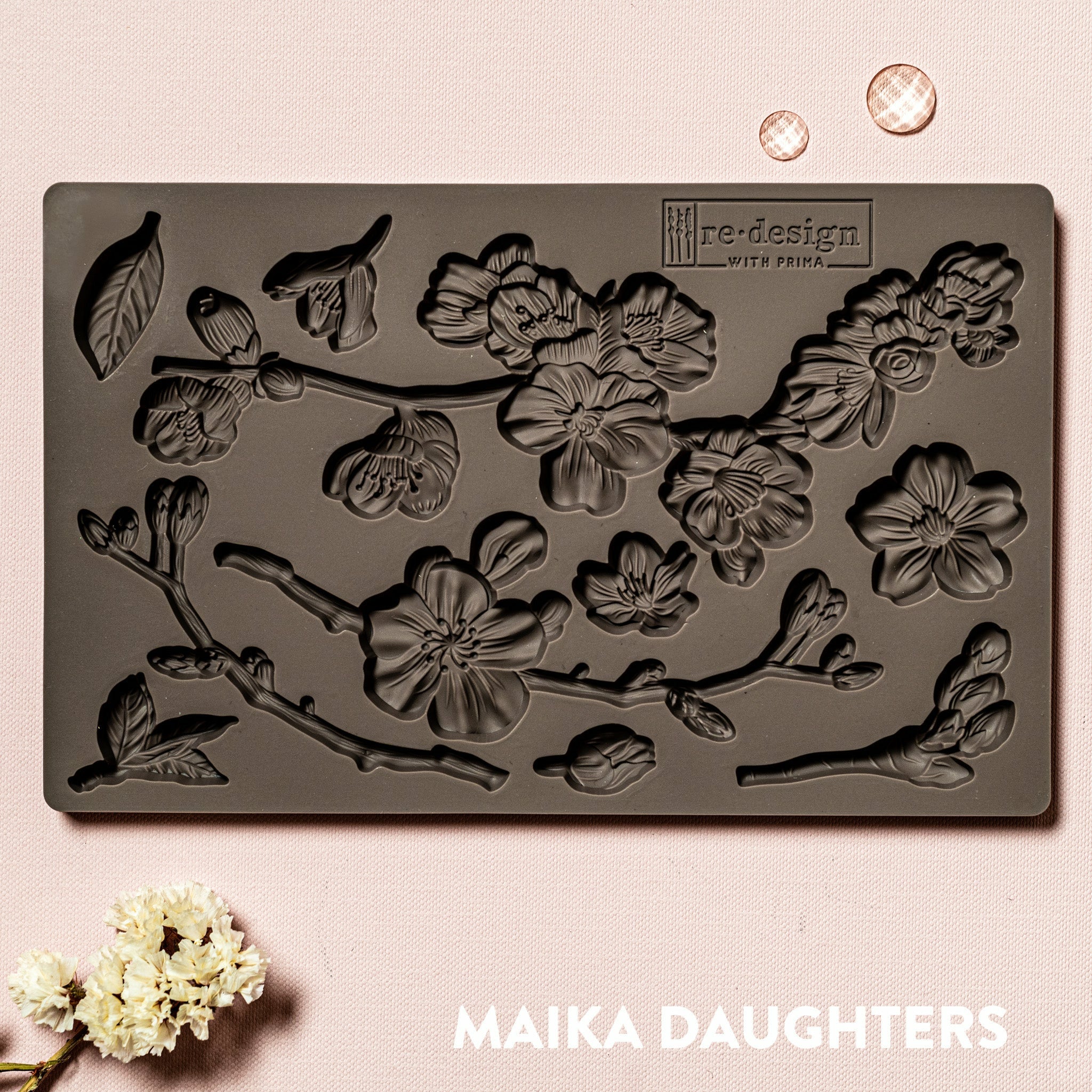 A brown silicone mould of ReDesign with Prima's Cherry Blossoms is against a light pink background.