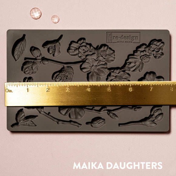 A brown silicone mould of ReDesign with Prima's Cherry Blossoms is against a light pink background. A gold ruler reading 8 inches sits on the mould.