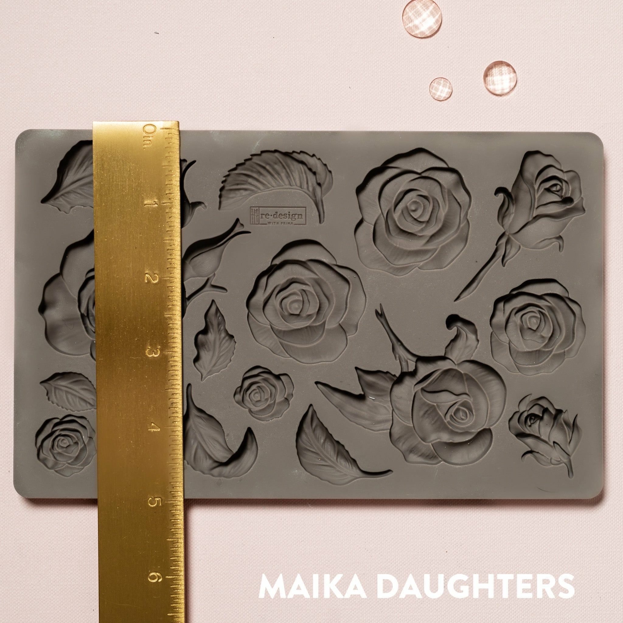 Brown silicone mould of ReDesign with Prima's Fragrant Roses is against a light pink background. A gold ruler reading 5 inches sits on the mould.
