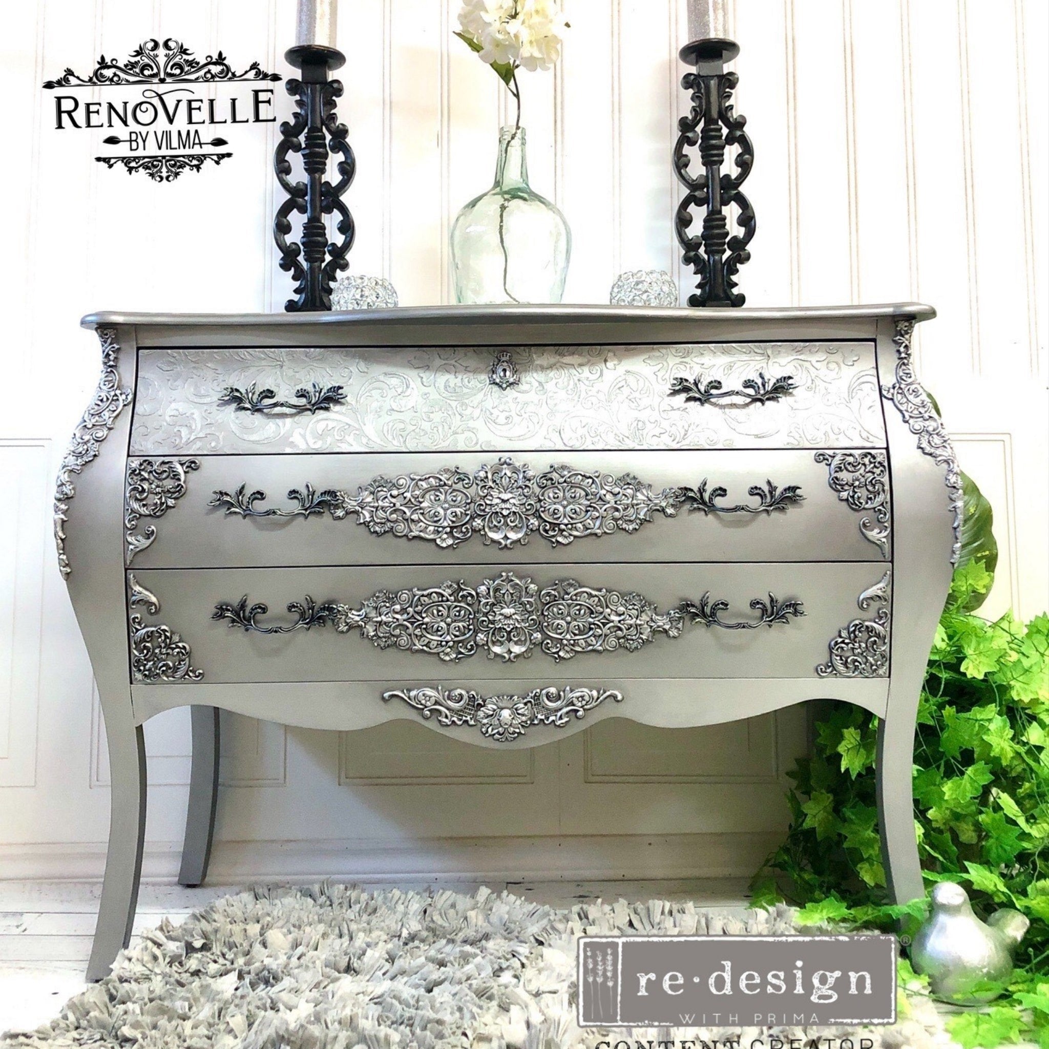 A vintage 3-drawer dresser refurbished by Renovelle by Vilma is painted silver and features the Golden Emblem silicone mould castings on it.