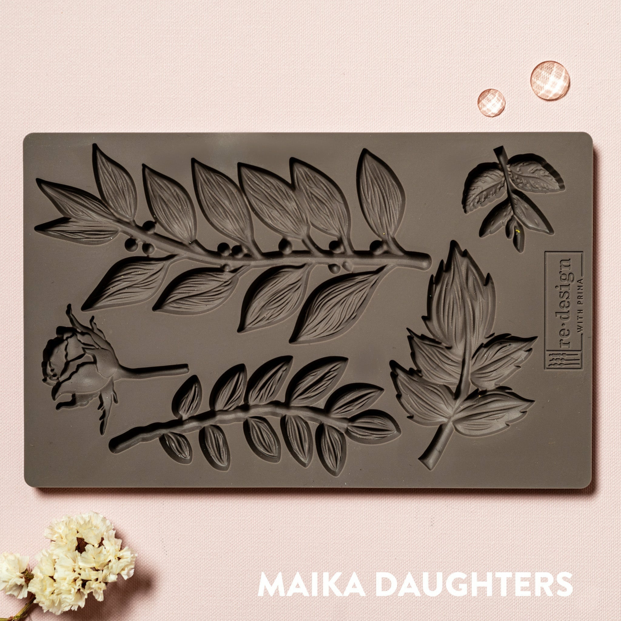 A brown silicone mould of ReDesign with Prima's Leafy Blossom is against a light pink background.