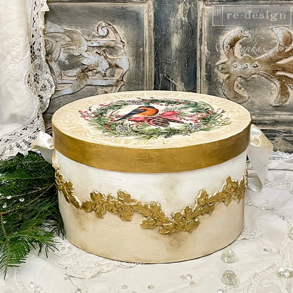 A circle box refurbished  by Bozenka Art is painted white with gold accents and features ReDesign with Prima's Louelle Borders in gold around the side.