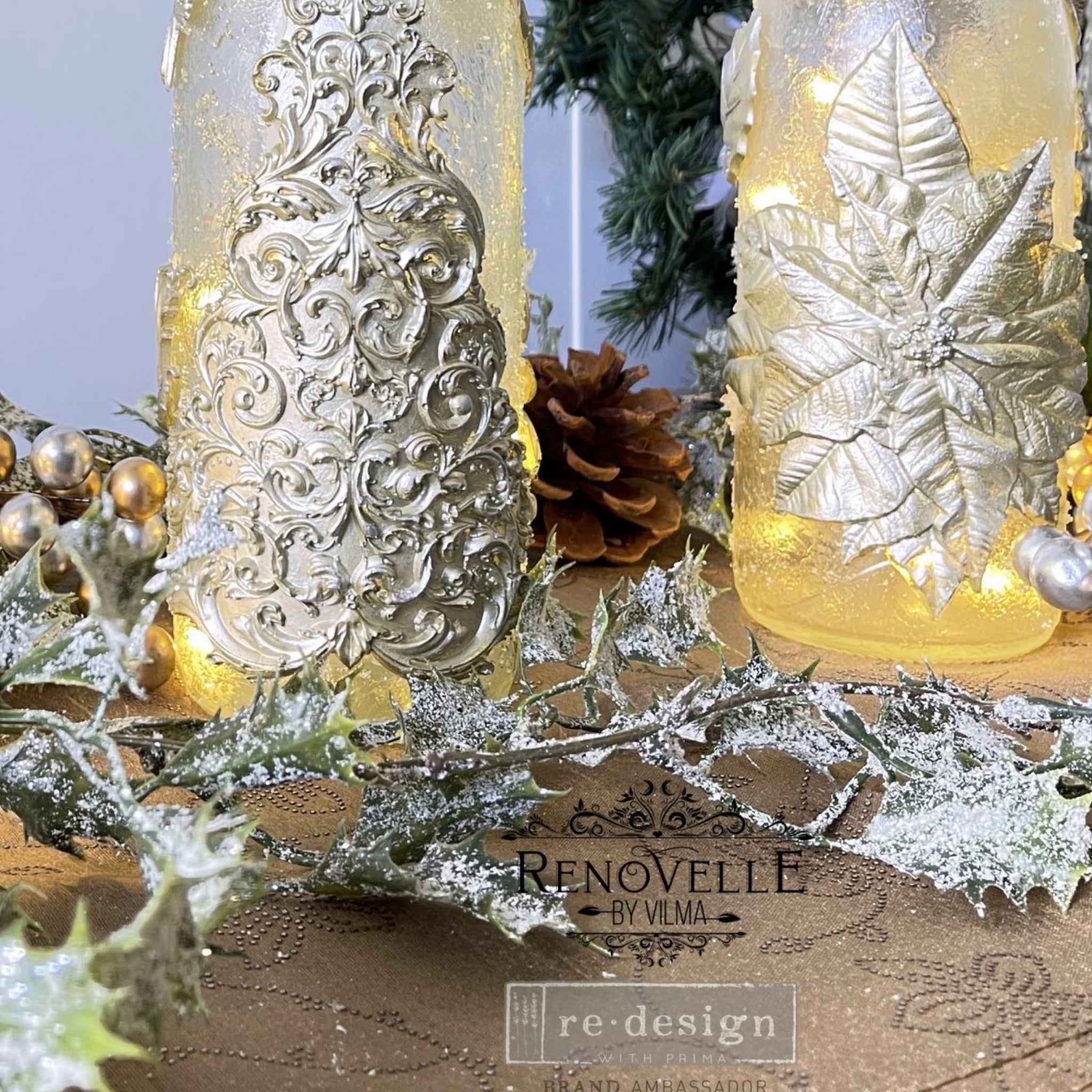 Two glass bottles refurbished by Renovelle by Vilma. One bottle features ReDesign with Prima's Perfect Poinsettia silicone mould casting in silver on it.