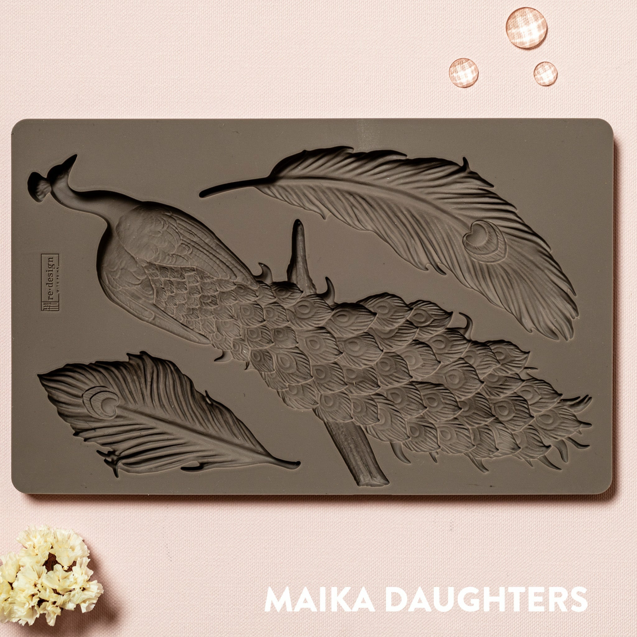 A brown silicone mould of ReDesign with Prima's Regal Peacock is against a light pink background.