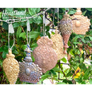 Six colorful castings of ReDesign with Prima's Victorian Adornments silicone mould are hanging in front of a vining plant.