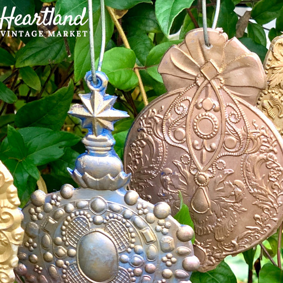 A close-up of ReDesign with Prima's Victorian Adornments silicone moulds against green foliage.