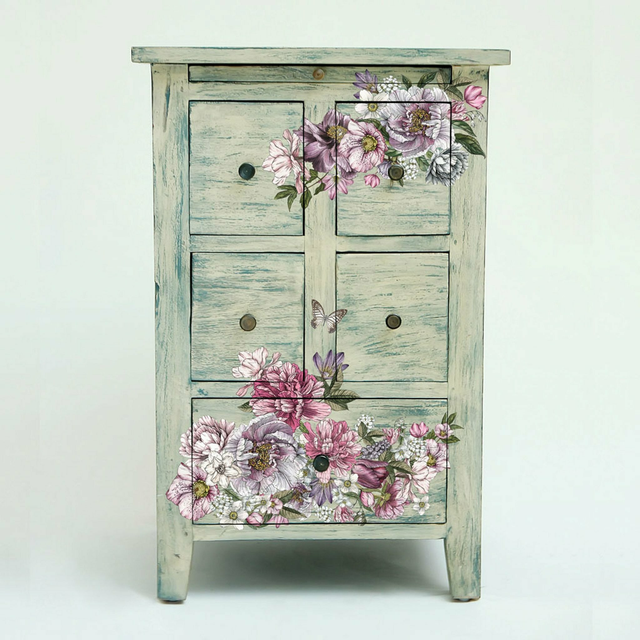 A blue stained tan dresser with the dreamy florals transfer placed on top of the drawers.