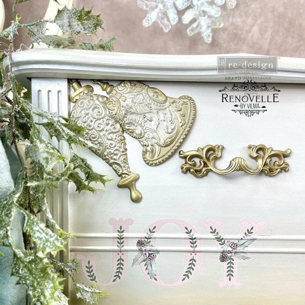 White dresser with the silver bells mold in gold. A transparent redesign brand ambassador logo and Renovelle by vilma logo on the top right.