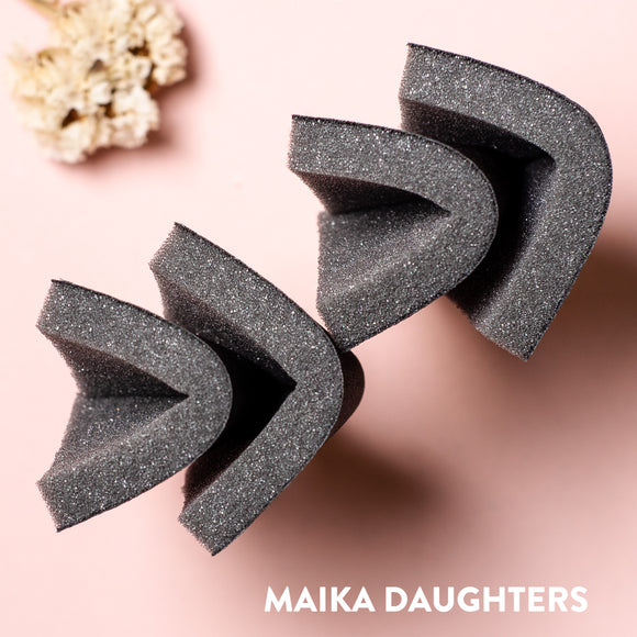 Four sanding sponges slightly folded in half against a light pink background.