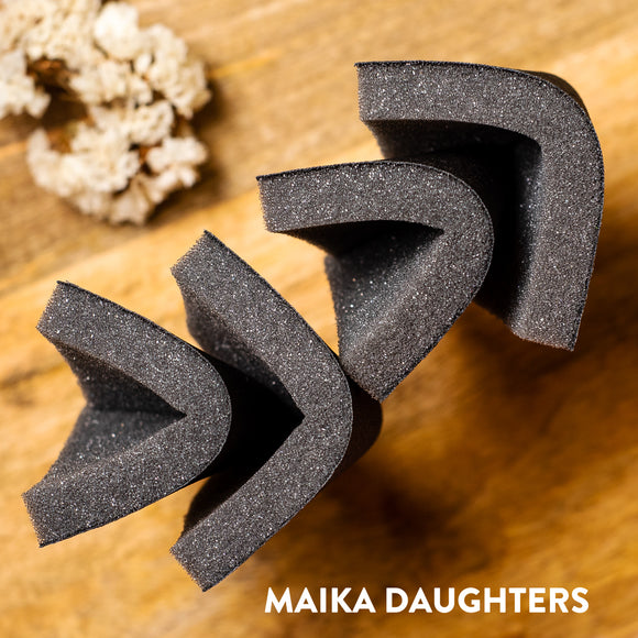 Four sanding sponges folded slightly in half against a wood table background.