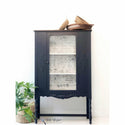 A dark navy blue dresser with the Lovely Ledger transfer on top. A black Click 2 restore your furniture your way logo on the bottom.