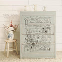 A light gray dresser with the Lovely Ledger transfer on top. A gray Then + Again Furniture Co. logo on the left.